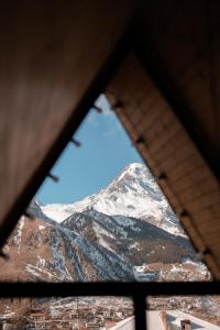 a view of a snow covered mountain through a window at SMART Via Kazbegi in Stepantsminda