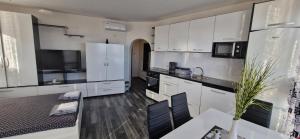 a kitchen with white cabinets and a table and a dining room at Black and White Apartment in Karlovo