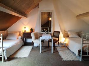 een slaapkamer met 2 bedden, een tafel en een spiegel bij B&B Maison Juves Planchez Anost Lac des Settons in Planchez