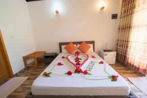 Una cama con un corazón hecho de flores. en Sabba Beach Suite , Fodhdhoo - Maldives en Velidhoo