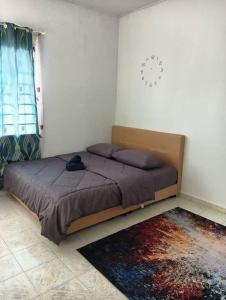 1 dormitorio con 1 cama en una habitación con reloj en la pared en Homestay HNH Melaka (Corner Lot), en Melaka