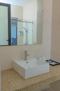 lavabo blanco en el baño con espejo en A Sim ba be lake hotel, en Bak Kan
