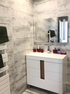 W łazience znajduje się biała umywalka i lustro. w obiekcie Appartement moderne au centre de Paris, 3ème w Paryżu