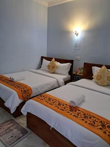 two beds with brown and white sheets in a room at Guesthouse Chamroeun Mongkul in Kampot