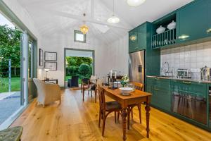 a kitchen with green cabinets and a wooden table at Augusta Hut in Auckland