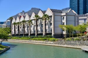 a building with palm trees in front of a river at City Lodge Hotel V&A Waterfront in Cape Town
