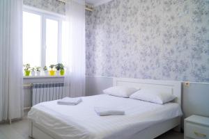 una camera da letto con un letto bianco con lenzuola bianche e una finestra di Гостиница, Ак-Буура a Bishkek