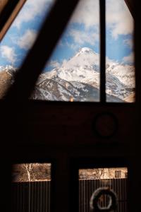una finestra con vista su una montagna innevata di Via Kazbegi a Kazbegi