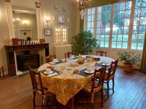 Manoir du Bellay في مونتري-بيلاي: غرفة طعام مع طاولة مع كراسي ومدفأة