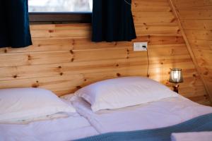 a bed in a room with a wooden wall at Via Kazbegi in Kazbegi