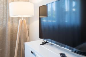 a flat screen tv sitting on top of a dresser with a lamp at MA-LIVING Miralior Apartment Mainz in Mainz
