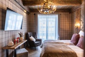 a bedroom with a bed and a chair and a chandelier at TatryTop Apartamenty Sobiczkowy Dwór in Zakopane