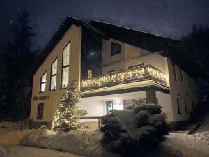 un edificio con un árbol de Navidad en la nieve en Vila Jensen, en Harrachov