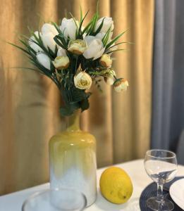Un jarrón con flores y un limón sobre una mesa. en The Best Choice Narva Center en Narva