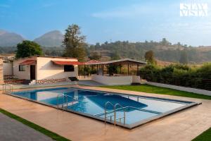 Villa con piscina y montañas de fondo en StayVista's Mango Splash - Mountain-View Retreat with Spacious Outdoor Pool, Lawn & Gazebo, en Karjat