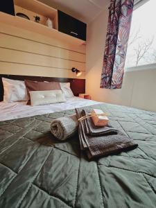 a bedroom with a bed with towels and a window at Bungalow Cosy équipé in La Boissière-de-Montaigu