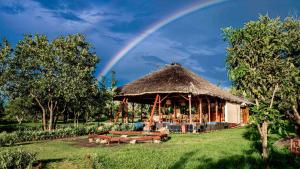 a large hut with a rainbow in the sky at Mama Washindi Lodge in Pakwach East