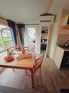 uma mesa de madeira e cadeiras numa pequena casa em Bungalow Cosy équipé em La Boissière-de-Montaigu