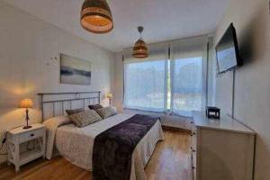 sypialnia z łóżkiem i telewizorem w obiekcie Apartamento con piscina w mieście Llanes