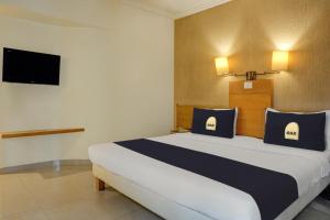 a bedroom with a large bed and a tv at Super Townhouse Oak Orchard Hotel in Pune
