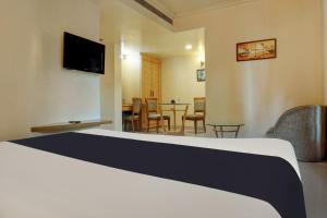 a hotel room with a bed and a table with chairs at Super Townhouse Oak Orchard Hotel in Pune