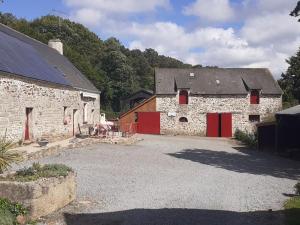 an old stone barn with red doors in a driveway at Gite à la ferme du chateau in Saint-Dolay