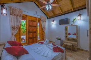 a bedroom with a bed with red pillows and a ceiling fan at Sabba Summer Suite , Fodhdhoo in Fodhdhoo