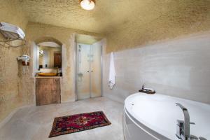Romantic Cave Hotel في نوشهر: حمام مع حوض استحمام ومغسلة