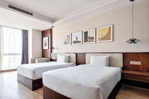 duas camas num quarto de hotel com lençóis brancos em MontClassic Hotel Chongqing em Chongqing