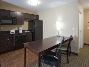 a kitchen with a table and a black refrigerator at GrandStay Hotel & Suites Thief River Falls in Thief River Falls