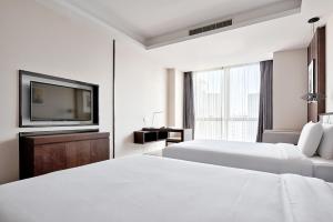 a white hotel room with two beds and a tv at MontClassic Hotel Chongqing in Chongqing