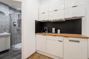 a white kitchen with a sink and a shower at A13- Deluxe Apartments, Best Location, by BQA in Budapest