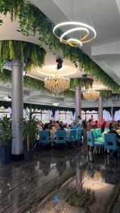 a dining room with people sitting at tables in a restaurant at Amelia Hotel in Almaty