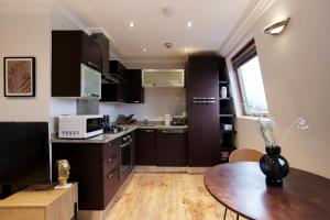 cocina con armarios negros y mesa de madera en The London Cradle - Spacious 1BDR Flat, en Londres