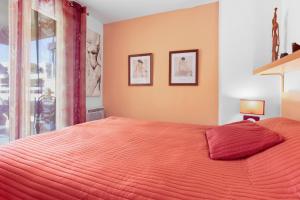 een slaapkamer met een oranje bed met twee foto's aan de muur bij Boulouris in Saint-Raphaël