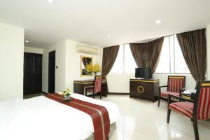 een hotelkamer met een bed en stoelen en een televisie bij LUCKY PALACE HOTEL in Bangkok