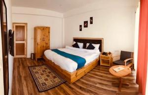 a bedroom with a king sized bed and a chair at Sankar Residency in Leh