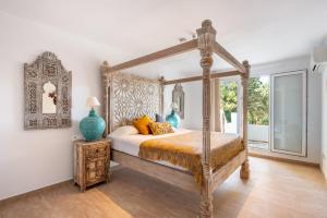 1 dormitorio con cama de madera con dosel y ventana en Villa Mediterraneo, en Sant Carles de Peralta