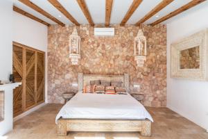 1 dormitorio con cama y pared de piedra en Villa Mediterraneo en Sant Carles de Peralta