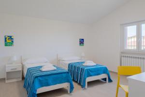 2 Betten in einem weißen Zimmer mit blauer Bettwäsche in der Unterkunft Haiku Rosa - YourPlace Abruzzo in Santa Maria Imbaro
