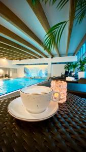 una tazza di caffè seduta su un tavolo accanto alla piscina di Andersia Hotel & Spa Poznan, a member of Radisson Individuals a Poznań