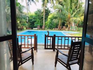 a view of a swimming pool from a porch with two chairs at Windy Garden in Galle