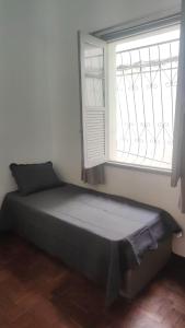 a bed sitting in a room with a window at Sôsouza in Belo Horizonte