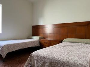 1 Schlafzimmer mit 2 Betten und einem Kopfteil aus Holz in der Unterkunft Casa mediterránea junto al mar. in Chilches
