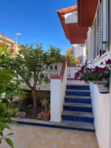 eine Treppe, die zu einem Gebäude mit einem Baum und Blumen führt in der Unterkunft Casa mediterránea junto al mar. in Chilches