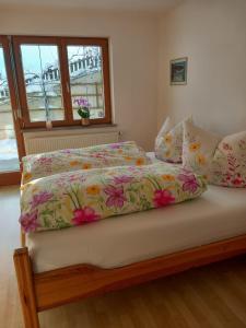 a bed with a floral comforter and pillows at Haus am Waldrand in Thiersee