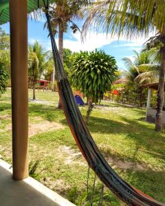 una hamaca en un parque con palmeras en Chalé Ilha Verde-Cumuruxatiba, en Cumuruxatiba