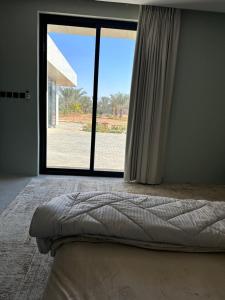 een slaapkamer met een bed en een groot raam bij مزرعة الخير 