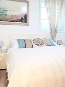 a white bed in a bedroom with a picture on the wall at Charming Central Ground Home just off Main ST! in Gibraltar