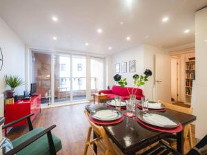 uma sala de estar com uma mesa e um sofá vermelho em Pass The Keys Modern 2-Bed Apartment with Private Balcony, Near Dalston Junction Station - Ideal Urban Retreat! em Londres